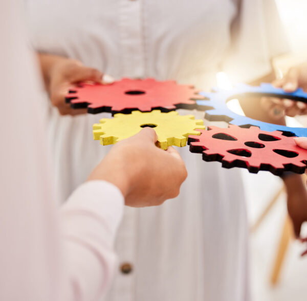 Success, collaboration and teamwork, people with gears on a table. Diversity, hands and a team of b.