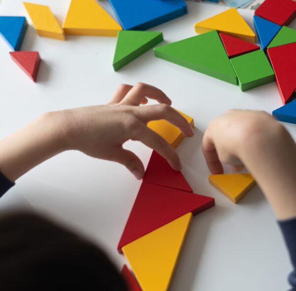 Kid playing with colorful wooden triangles, developing fine motor skills and creativity through educational game