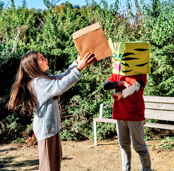 children with heads in cardboard box, playing in the park