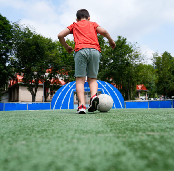 A young boy prepares to kick a soccer ball on a sunny field. Concept of practice, focus, and youth in sports.